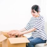 段ボールに服を入れる女性