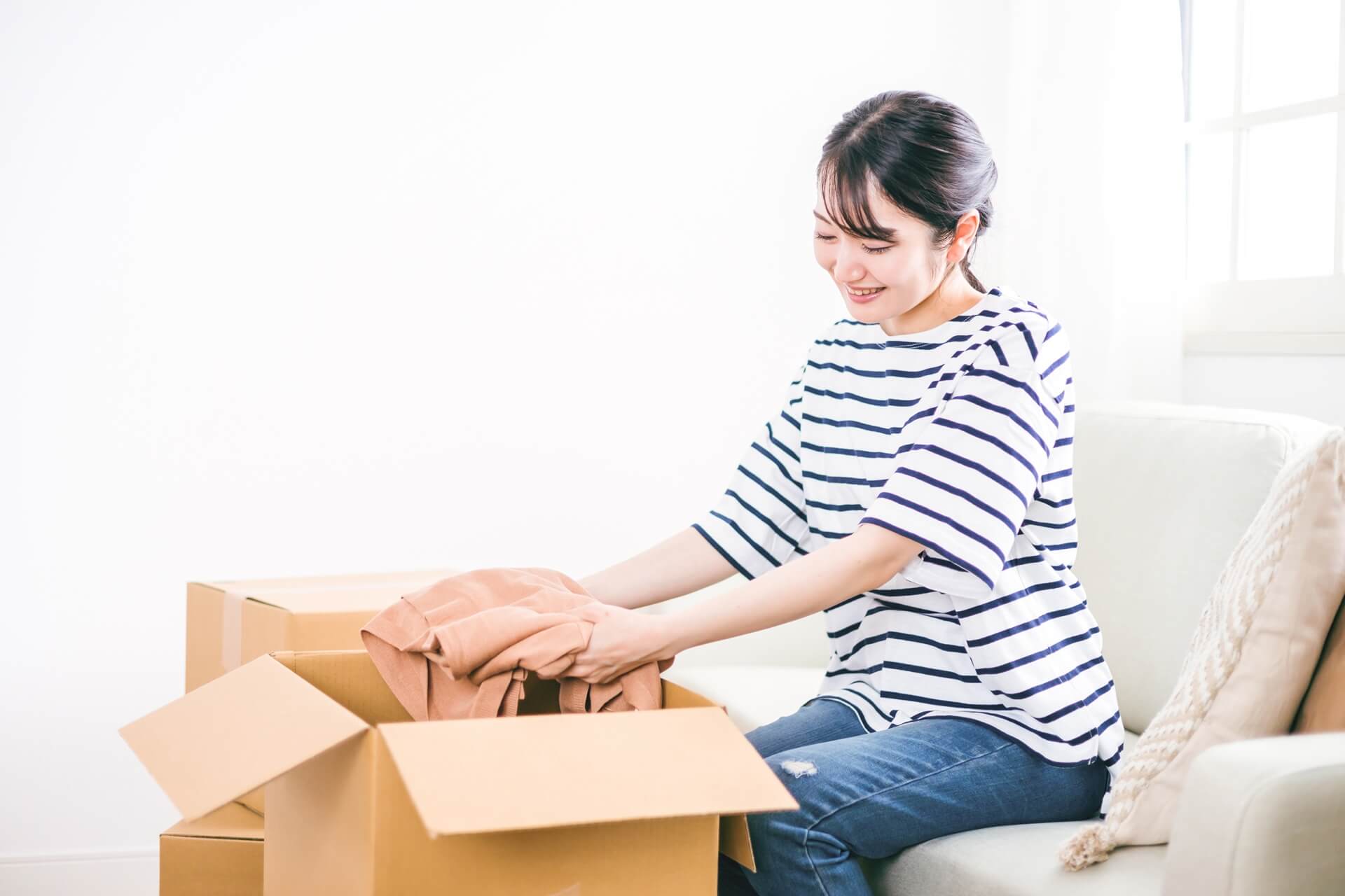 段ボールに服を入れる女性
